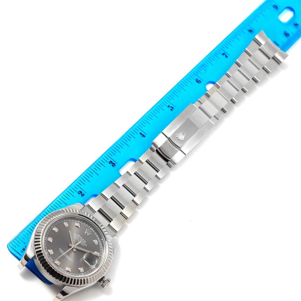 The Rolex Datejust 41 116334 Men's Stainless Steel Grey Dial 116334 Men's Stainless Steel Grey Dial watch is shown laid flat with its silver bracelet alongside a blue ruler for measurement.