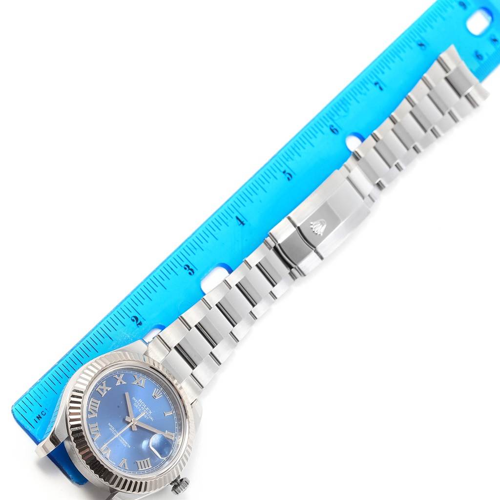 The image shows a Rolex Datejust 41 116334 Men's Stainless Steel Blue Dial 116334 Men's Stainless Steel Blue Dial watch with a blue dial and a silver bracelet, placed next to a blue ruler.