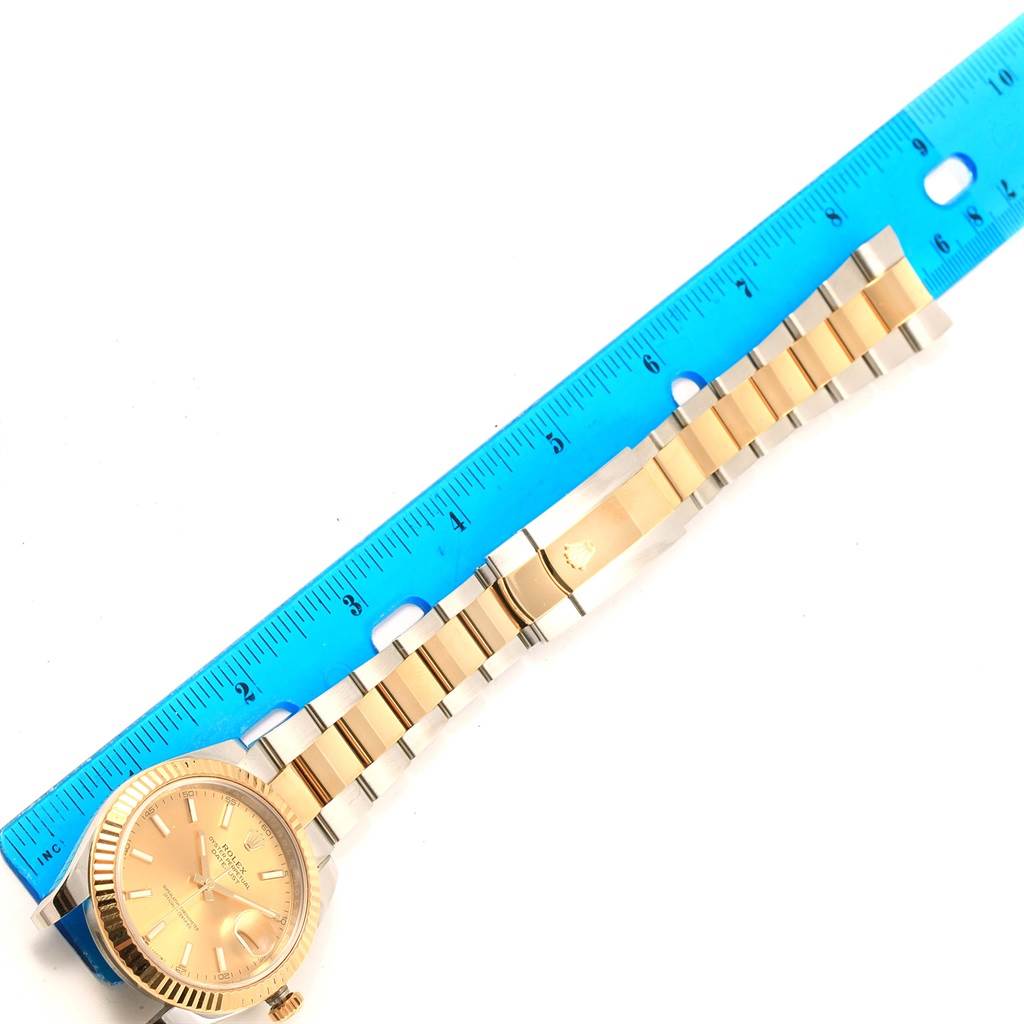 The Rolex Datejust 41 126333 Men's Steel and Gold (two tone) Champagne Dial 126333 Men's Steel and Gold (two tone) Champagne Dial watch is shown from a top-down angle, displaying the dial, bezel, and part of the bracelet alongside a ruler.