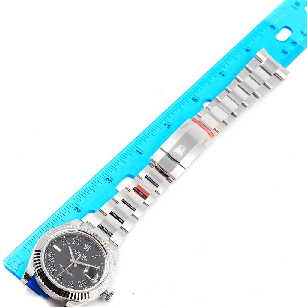 This image shows a top view of a Rolex Datejust 41 116334 Men's Stainless Steel Grey Dial 116334 Men's Stainless Steel Grey Dial watch, highlighting its face, bracelet, and clasp, next to a blue ruler.