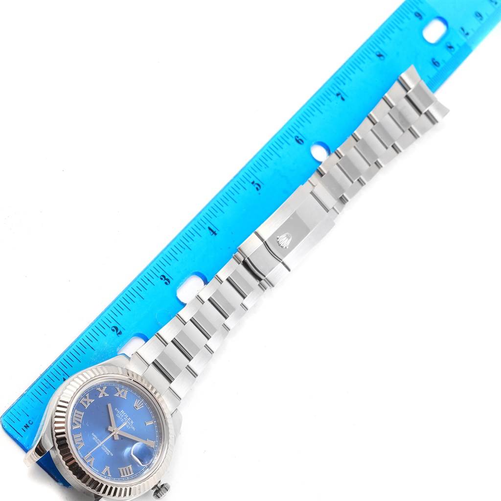 The image shows a Rolex Datejust 41 116334 Men's Stainless Steel Blue Dial 116334 Men's Stainless Steel Blue Dial watch with a blue dial and Roman numerals, displayed with its bracelet stretched out alongside a ruler.