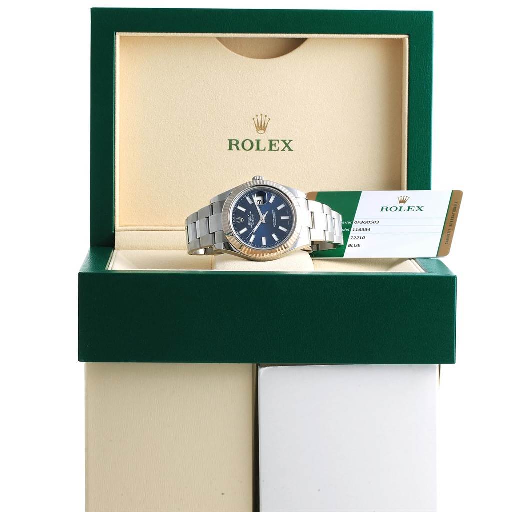 The Rolex Datejust 41 116334 Men's Stainless Steel Blue Dial 116334 Men's Stainless Steel Blue Dial watch is displayed in its box, resting with its face angled slightly upwards, alongside a green and white Rolex card.