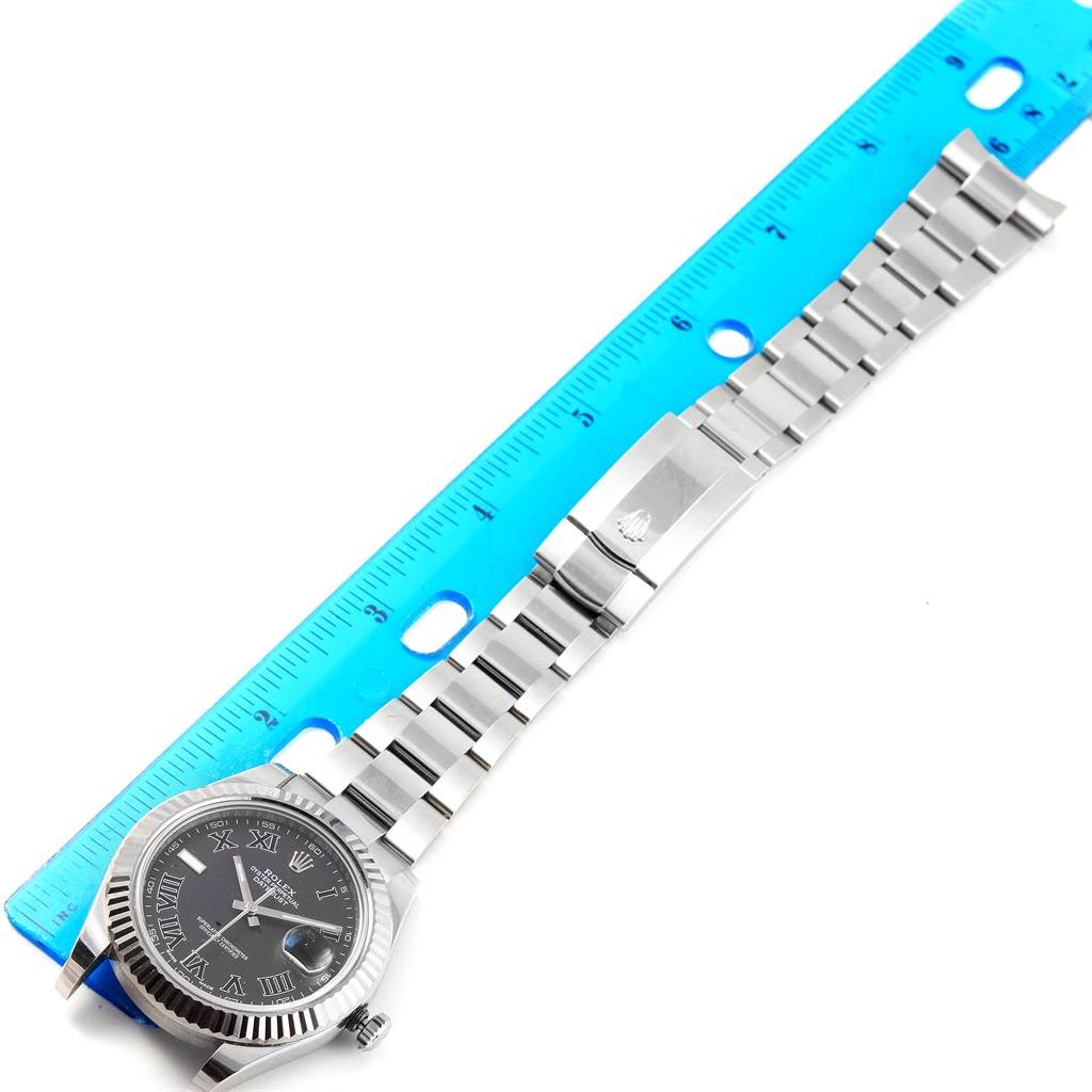 The Rolex Datejust 41 116334 Men's Stainless Steel Grey Dial 116334 Men's Stainless Steel Grey Dial watch is shown lying flat with its face, bezel, bracelet, and clasp visible, aligned next to a ruler.