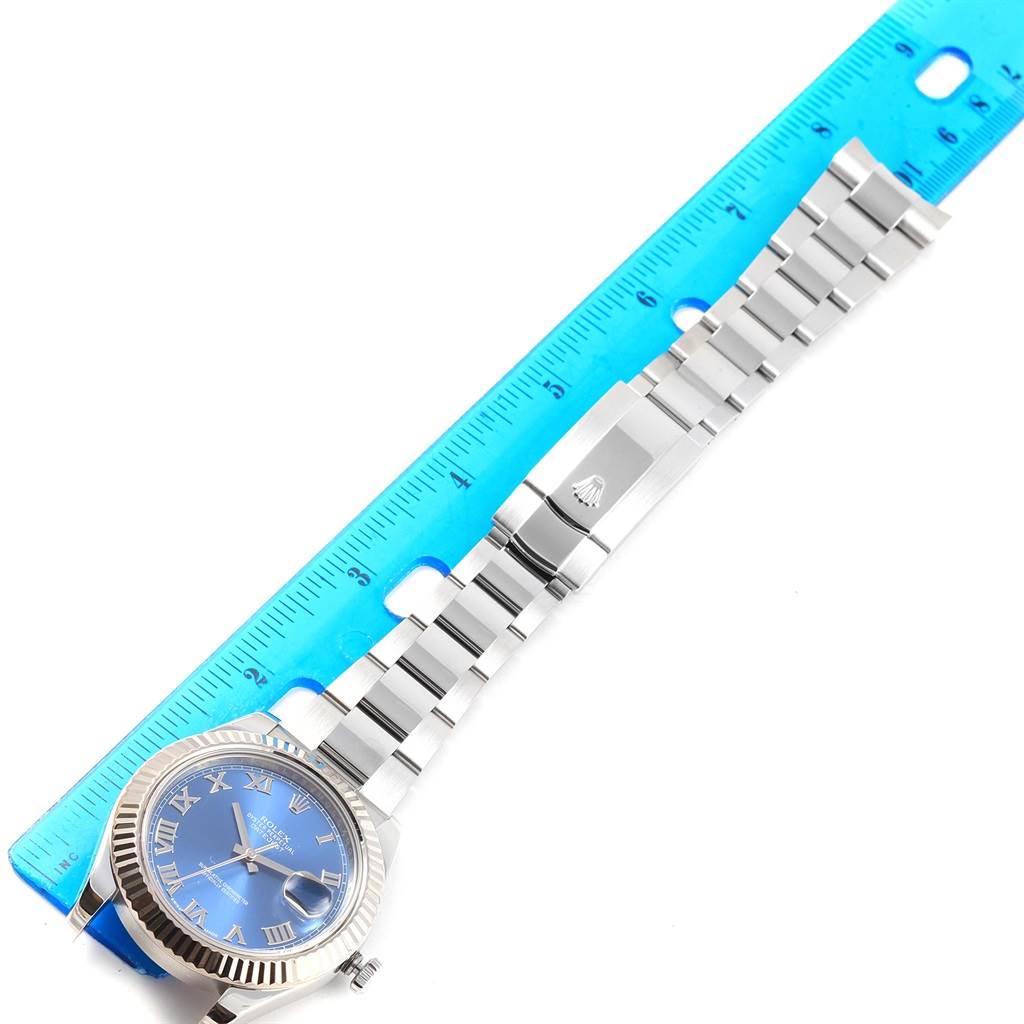 The image shows a top-down view of a Rolex Datejust 41 116334 Men's Stainless Steel Blue Dial 116334 Men's Stainless Steel Blue Dial watch with a blue dial and roman numerals, placed next to a blue ruler.