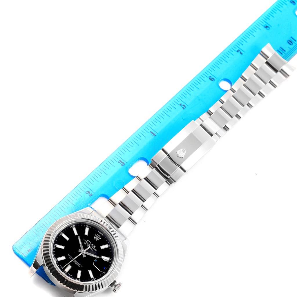 The image shows the Rolex Datejust 41 116334 Men's Stainless Steel Black Dial 116334 Men's Stainless Steel Black Dial watch at a top-down angle, displaying its bracelet and part of its face with a blue ruler for scale.