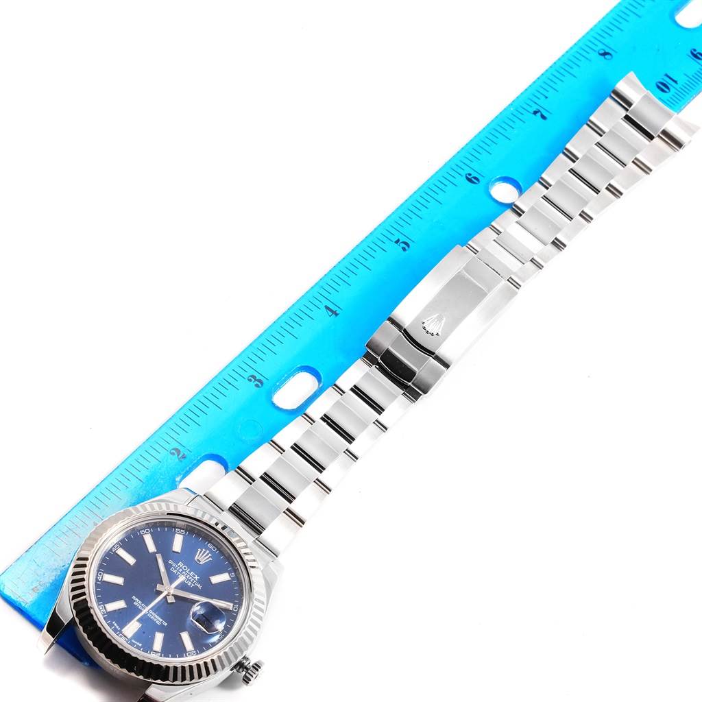 The Rolex Datejust 41 116334 Men's Stainless Steel Blue Dial 116334 Men's Stainless Steel Blue Dial model is shown from an overhead angle, displaying the watch face, bracelet, and clasp alongside a ruler.