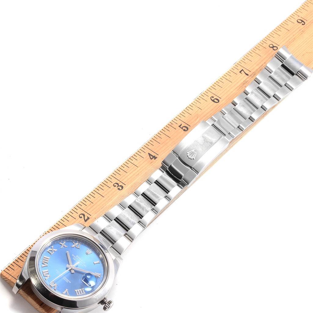 The Rolex Datejust 41 116300 Men's Stainless Steel Blue Dial 116300 Men's Stainless Steel Blue Dial watch is shown from a top-down angle, displaying its blue dial, Roman numerals, and metal bracelet alongside a ruler.