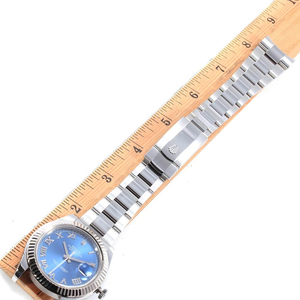 The Rolex Datejust 41 116334 Men's Stainless Steel Blue Dial 116334 Men's Stainless Steel Blue Dial watch is shown from the top, displaying the blue dial, metal bracelet, and clasp against a ruler.