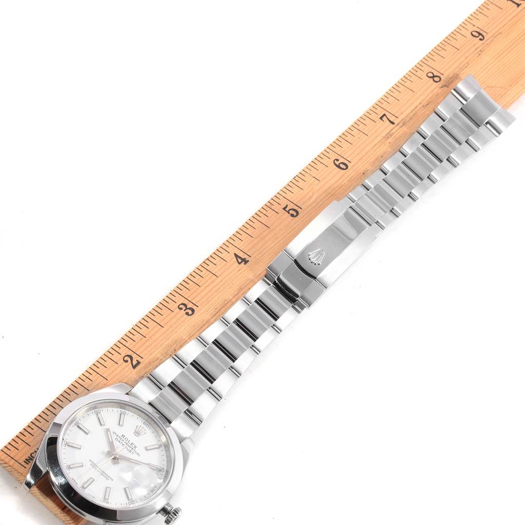 A Rolex Datejust 41 126300 Men's Stainless Steel White Dial 126300 Men's Stainless Steel White Dial watch is shown from a top-down view, including the face, bracelet, and clasp alongside a ruler.