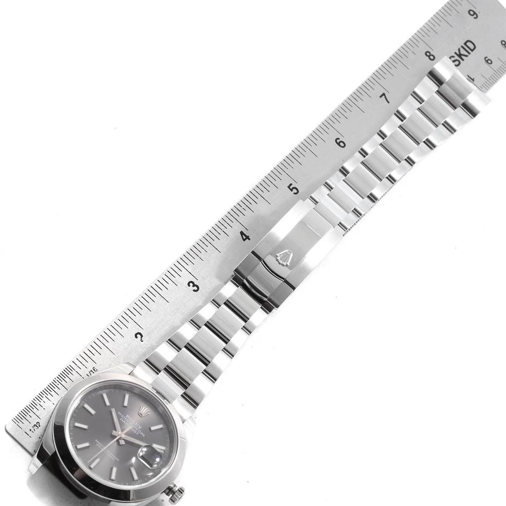 The image shows a top-down view of the Rolex Datejust 41 126300 Men
s Stainless Steel Grey Dial 126300 Men
s Stainless Steel Grey Dial watch, featuring its face, bracelet, and clasp next to a ruler for scale.