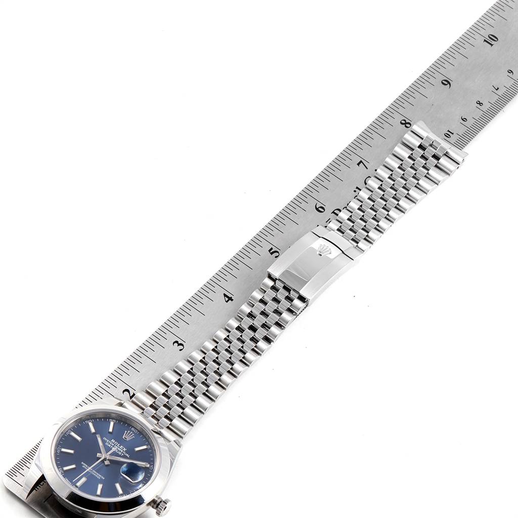 The Rolex Datejust 41 126300 Men's Stainless Steel Blue Dial 126300 Men's Stainless Steel Blue Dial watch is shown from a top-down view, highlighting the face, bracelet, and clasp next to a ruler for scale.