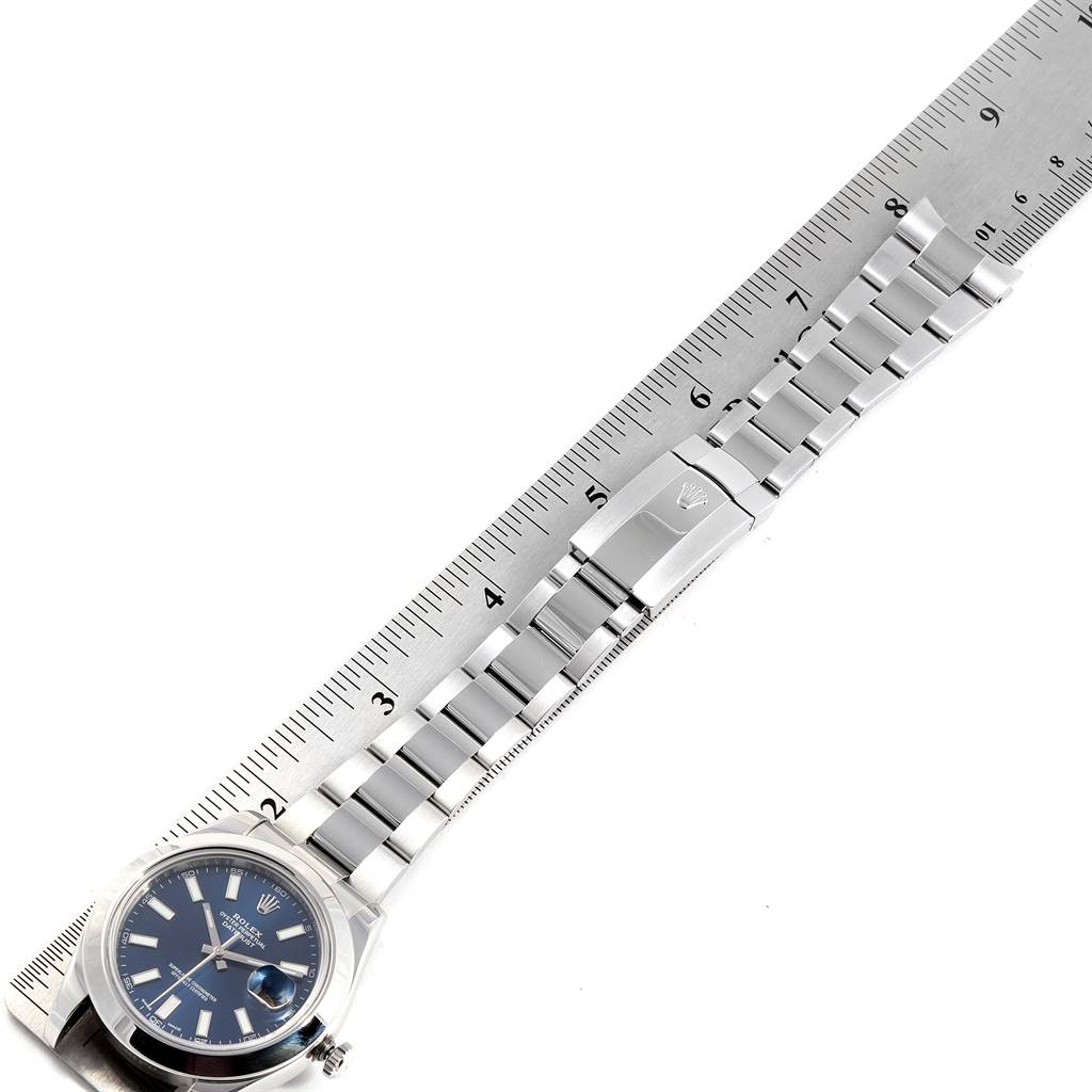 The image shows a top view of a Rolex Datejust 41 116300 Men
s Stainless Steel Blue Dial 116300 Men
s Stainless Steel Blue Dial watch, focusing on the face, bracelet, and clasp, with a ruler for scale.