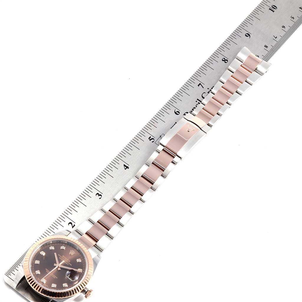The image shows a top view of a Rolex Datejust 41 126331 Men's Steel and Gold (two tone) Brown Dial 126331 Men's Steel and Gold (two tone) Brown Dial watch, highlighting its strap aligned with a ruler.