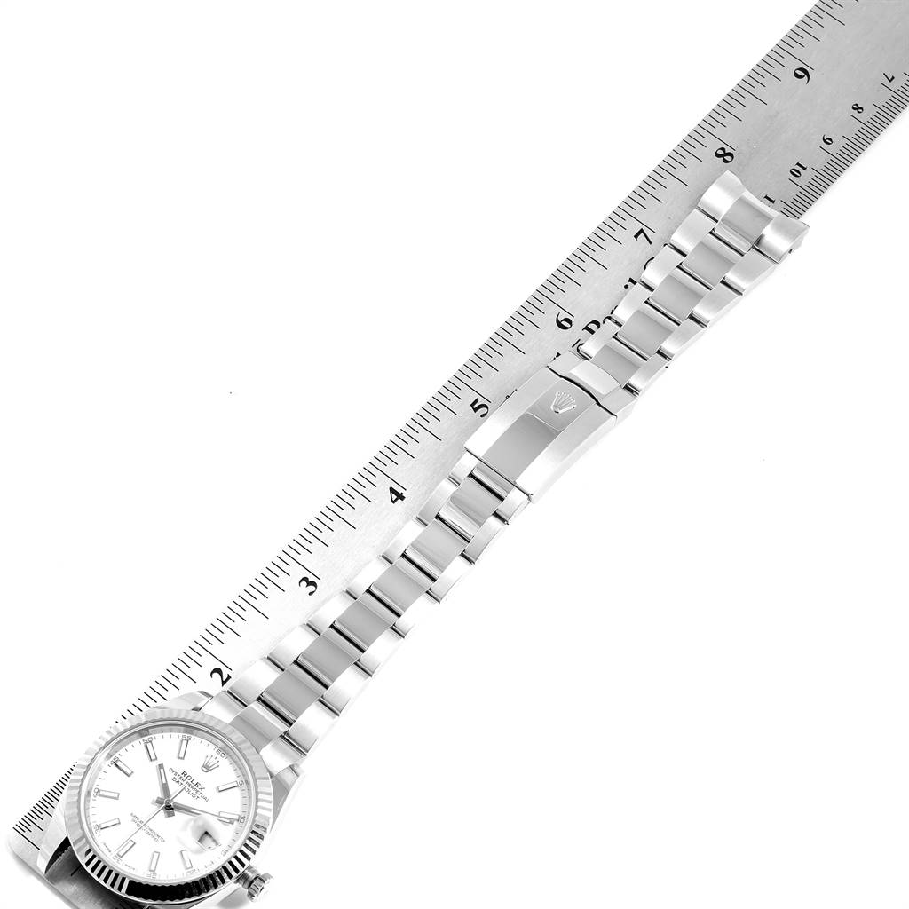 The image shows the Rolex Datejust 41 126334 Men's Stainless Steel White Dial 126334 Men's Stainless Steel White Dial watch laid next to a ruler, highlighting its bracelet and clasp.