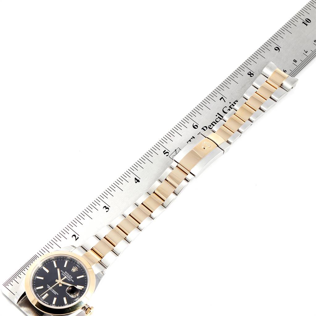 The Rolex Datejust 41 126303 Men's Steel and Gold (two tone) Black Dial 126303 Men's Steel and Gold (two tone) Black Dial watch is shown from a top-down angle alongside a ruler.