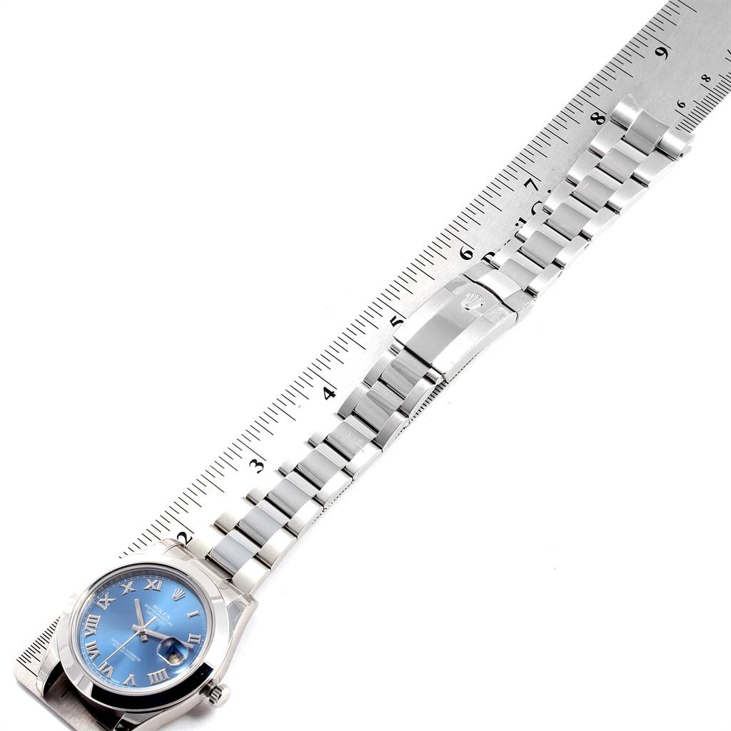 The image shows a top-down view of a Rolex Datejust 41 116300 Men's Stainless Steel Blue Dial 116300 Men's Stainless Steel Blue Dial watch with a blue dial and its stainless steel bracelet laid next to a ruler.