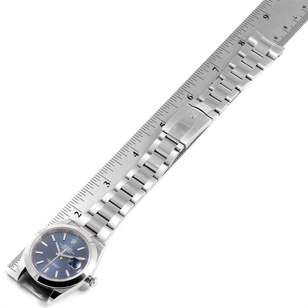 This image shows a Rolex Datejust 41 126300 Men's Stainless Steel Blue Dial 126300 Men's Stainless Steel Blue Dial watch laid flat with a metal bracelet fully extended along a ruler.