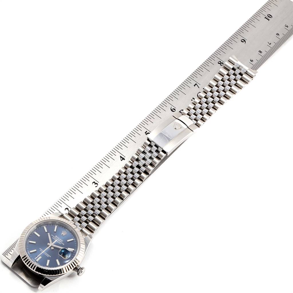 This image shows the Rolex Datejust 41 126334 Men's Stainless Steel Blue Dial 126334 Men's Stainless Steel Blue Dial watch laid flat with a ruler, highlighting its face, bracelet, and clasp.