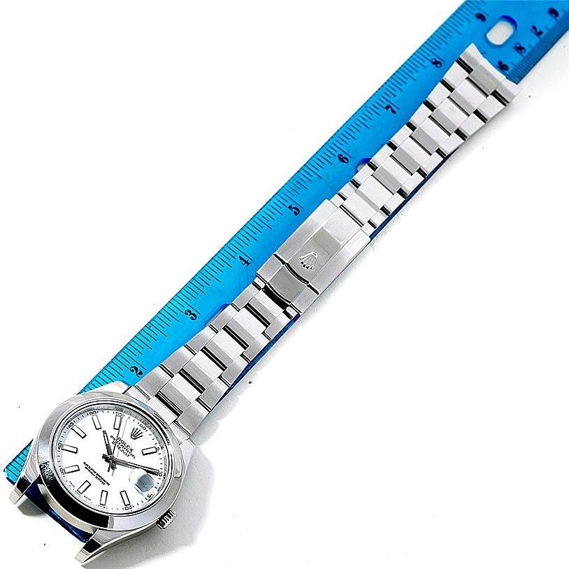 This image shows a top-down view of the Rolex Datejust 41 116300 Men's Stainless Steel White Dial 116300 Men's Stainless Steel White Dial watch model placed beside a blue ruler.