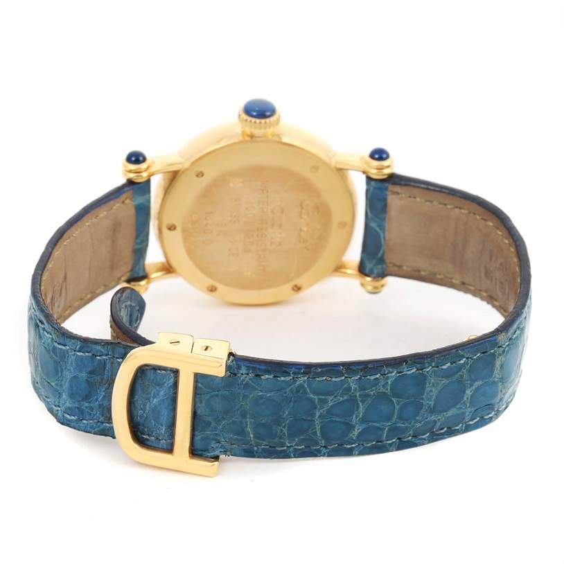 The Cartier Diabolo 1400 Women
s Yellow Gold Silver Dial 1400 Women
s Yellow Gold Silver Dial watch is shown from the rear, featuring its caseback, blue strap, and gold clasp.