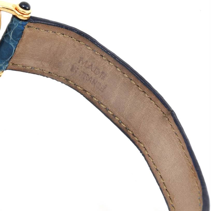 The image shows the underside of the leather strap and part of the gold case of the Diabolo watch by Cartier at an angle.