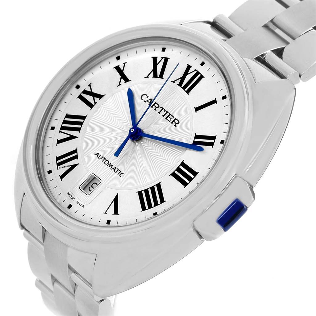 The Cartier Clé watch is shown at an angled view displaying the face, Roman numerals, blue hands, date window, and part of the bracelet.