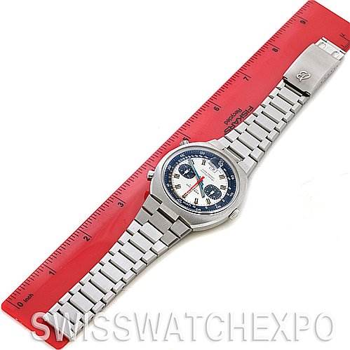 The image shows a top-down view of a Breitling Transocean 2129 Men's Stainless Steel Silver Dial 2129 Men's Stainless Steel Silver Dial watch with its stainless steel bracelet placed on a red ruler.