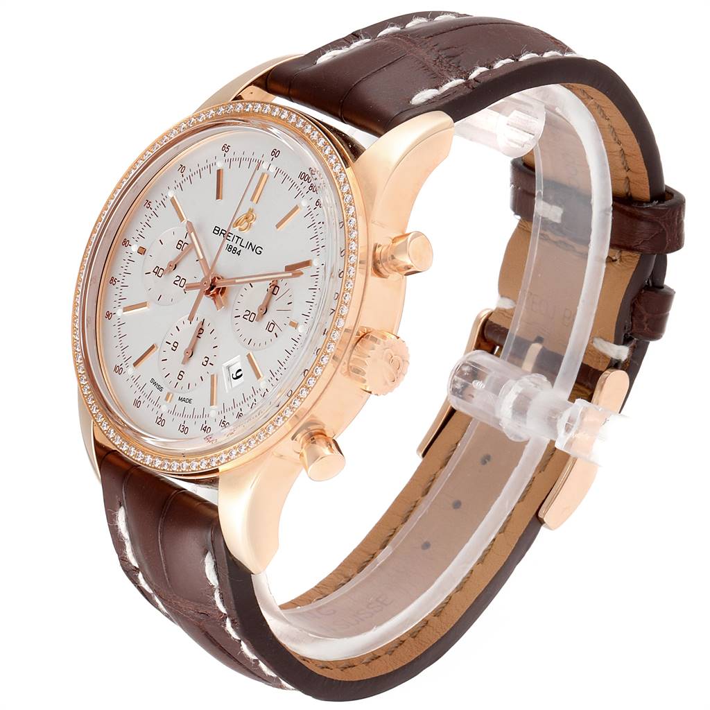 This image shows a Breitling Transocean RB0152 Men's Rose Gold Silver Dial RB0152 Men's Rose Gold Silver Dial model watch from a three-quarter angle, highlighting its face, bezel, crown, and leather strap.