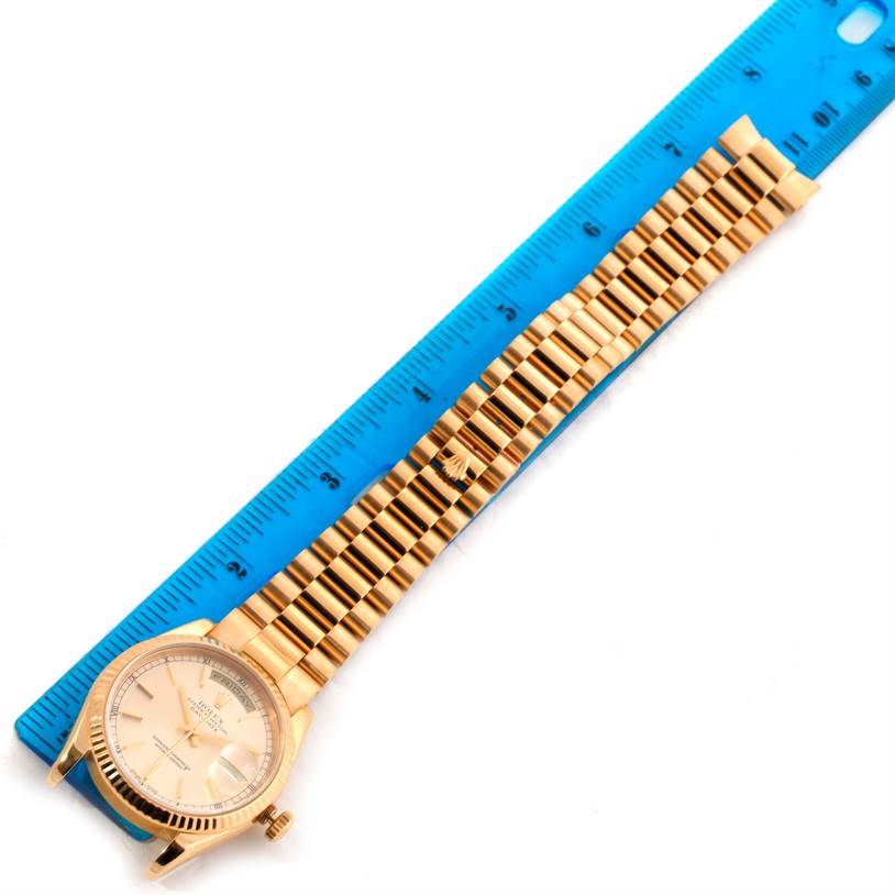 This image shows a Rolex President 118238 Men's Yellow Gold Silver Dial 118238 Men's Yellow Gold Silver Dial model watch displayed next to a blue ruler, highlighting the watch face and metal bracelet.