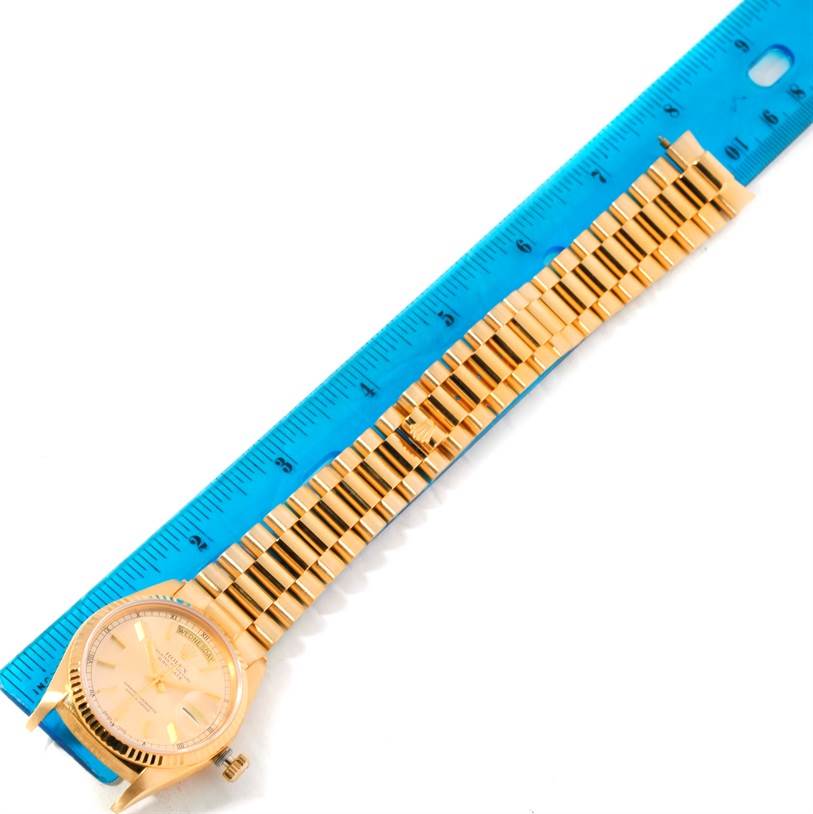 The image shows a top view of a Rolex President 18038 Men
s Yellow Gold Silver Dial 18038 Men
s Yellow Gold Silver Dial model watch, including its face, bezel, and gold bracelet, placed next to a ruler.