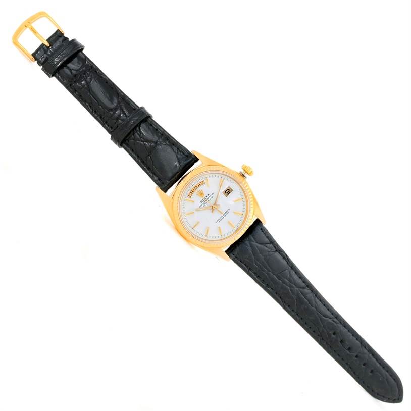 The Rolex President 1803 Men
s Yellow Gold White Dial 1803 Men
s Yellow Gold White Dial watch is shown from a top-down angle, displaying the dial, case, crown, and black leather strap.