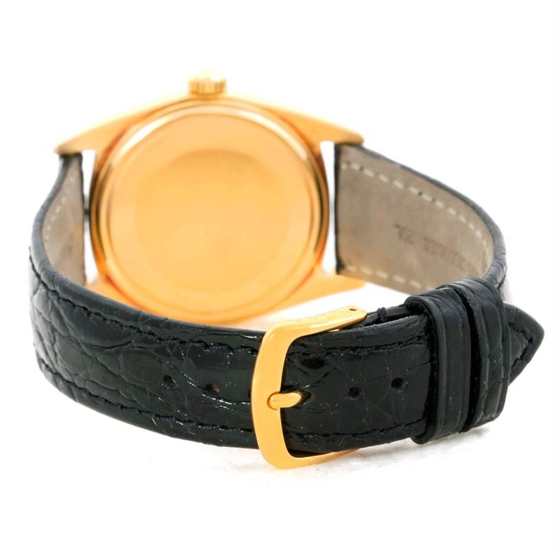 The image shows the back view of a Rolex President 1803 Men
s Yellow Gold White Dial 1803 Men
s Yellow Gold White Dial model watch, focusing on its gold case and black leather strap with a gold buckle.
