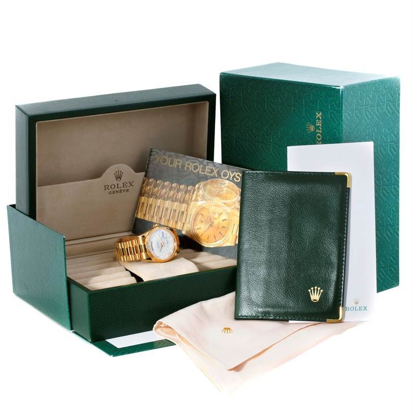 The image shows a Rolex President 118238 Men
s Yellow Gold White Dial 118238 Men
s Yellow Gold White Dial model watch with its box, booklet, cleaning cloth, and warranty card holder.
