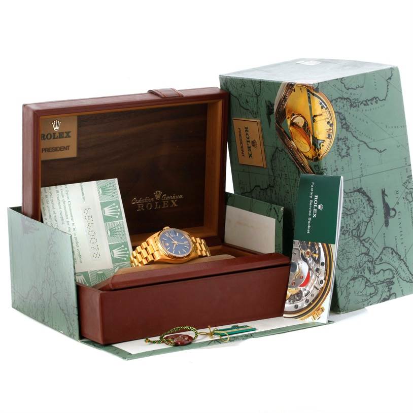 The image shows a Rolex President 18038 Men's Yellow Gold Blue Dial 18038 Men's Yellow Gold Blue Dial model watch in its box, with papers and accessories displayed around it.