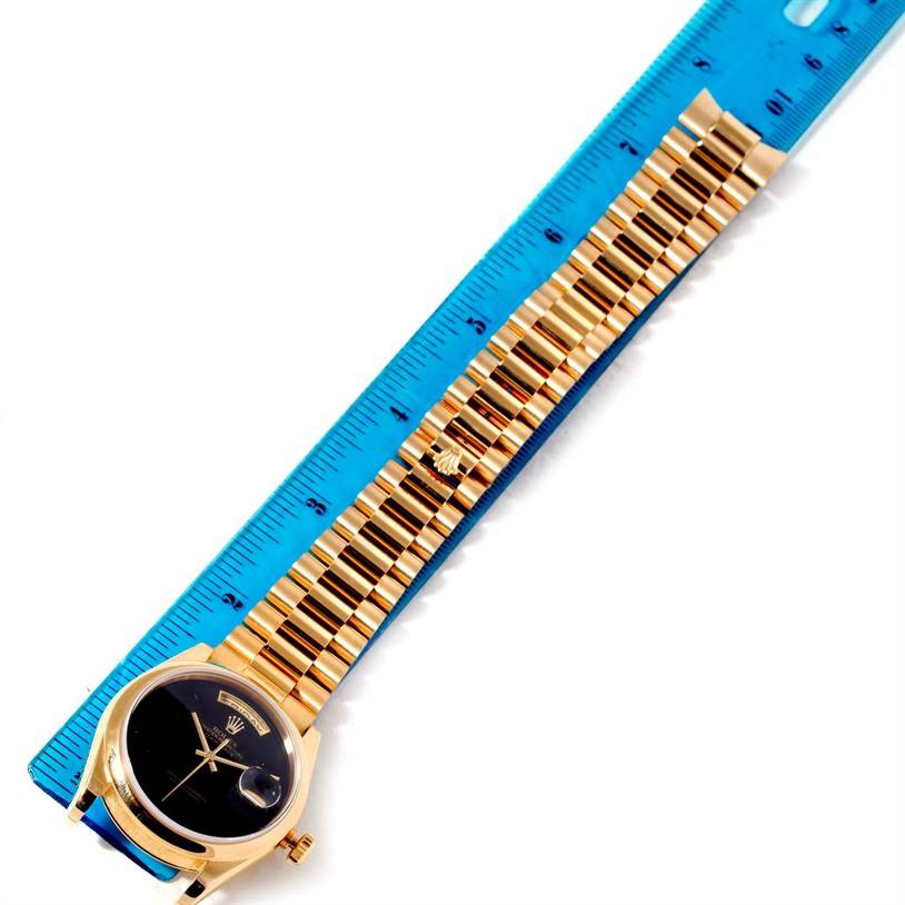 The image shows a Rolex President 118208 Men's Yellow Gold Black Dial 118208 Men's Yellow Gold Black Dial model watch placed next to a ruler, featuring the dial and bracelet.