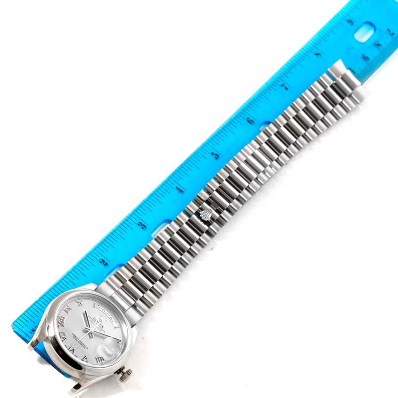 The image shows a top-down view of a Rolex President 118209 Men's White Gold Silver Dial 118209 Men's White Gold Silver Dial model watch with its bracelet next to a blue ruler for scale.