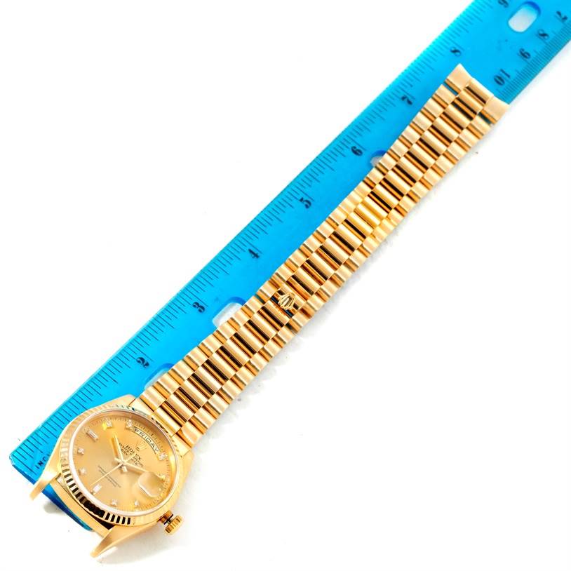 The image shows a Rolex President 18238 Men
s Yellow Gold Champagne Dial 18238 Men
s Yellow Gold Champagne Dial model watch placed alongside a blue ruler, highlighting the band and dial from a top-down angle.