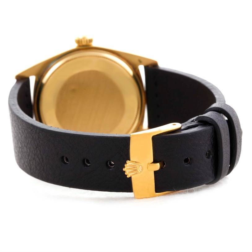 The image shows the back view of a Rolex President 1803 Men
s Yellow Gold Champagne Dial 1803 Men
s Yellow Gold Champagne Dial watch with a black leather strap and gold clasp.