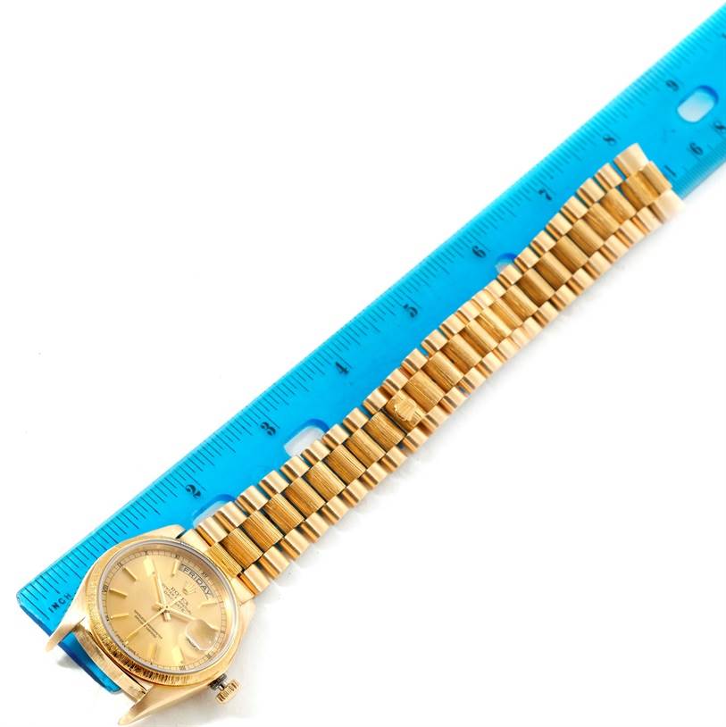 The Rolex President 18078 Yellow Gold Champagne Dial 18078 Yellow Gold Champagne Dial watch is shown from a top view, with its face and bracelet aligned next to a blue ruler.