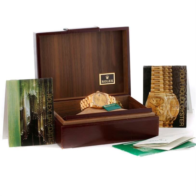 The image shows a Rolex President 18238 Men
s Yellow Gold Champagne Dial 18238 Men
s Yellow Gold Champagne Dial model watch inside an open wooden box with accompanying booklets displayed around it.