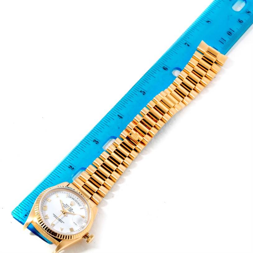 The image shows a Rolex President 18238 Men's Yellow Gold White Dial 18238 Men's Yellow Gold White Dial model watch laid flat with the bracelet extended next to a blue ruler.