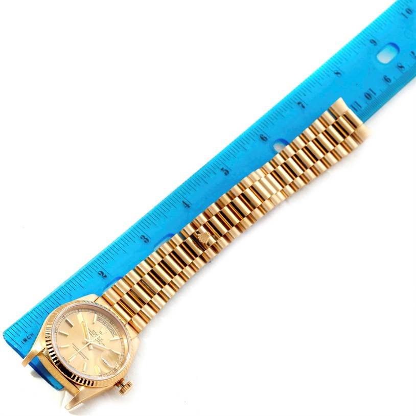 This image shows a Rolex President 18238 Men's Yellow Gold Champagne Dial 18238 Men's Yellow Gold Champagne Dial model watch with a gold bracelet laid next to a blue ruler for measurement.