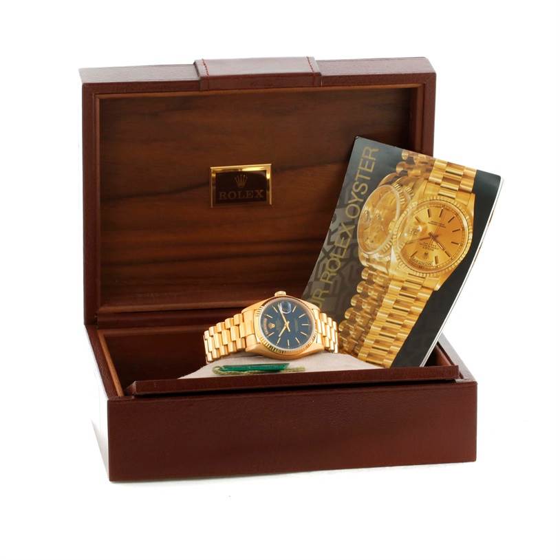 The image shows a Rolex President 18038 Men's Yellow Gold Blue Dial 18038 Men's Yellow Gold Blue Dial model watch displayed in an open wooden box, accompanied by a promotional booklet.