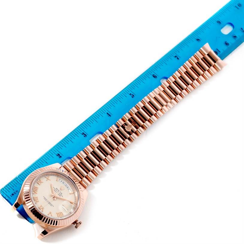 This image shows a top-down view of a Rolex President 218235 Men's Rose Gold Beige Dial 218235 Men's Rose Gold Beige Dial model watch with its face and bracelet aligned next to a blue ruler.