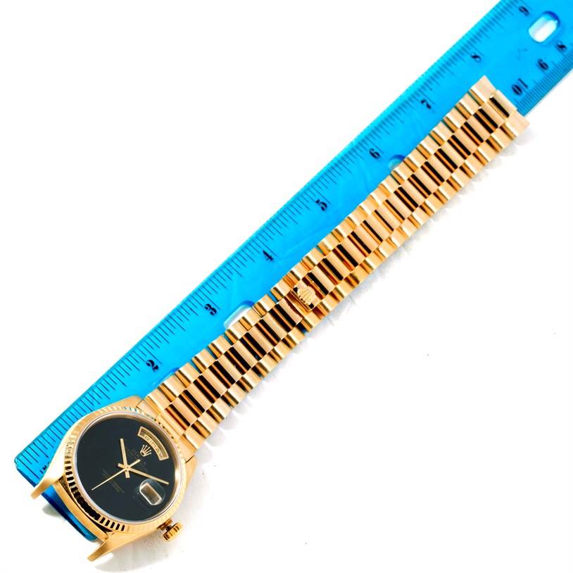 This image shows a flat-lay view of the Rolex President 18238 Men
s Yellow Gold Champagne Dial 18238 Men
s Yellow Gold Champagne Dial model watch with its strap extended alongside a ruler.