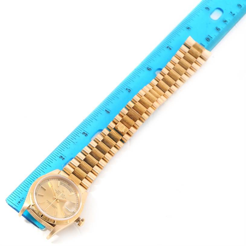 The image shows a top-down view of a Rolex President 18248 Men
s Yellow Gold Champagne Dial 18248 Men
s Yellow Gold Champagne Dial watch, including its face and gold bracelet, beside a blue ruler for size reference.