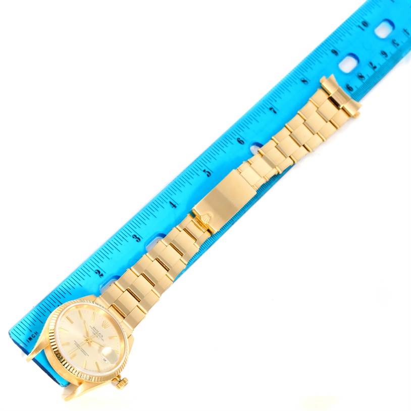 The image shows a Rolex President 15238 Men
s Yellow Gold Silver Dial 15238 Men
s Yellow Gold Silver Dial model watch laid flat next to a blue ruler, displaying its entire length and bracelet.
