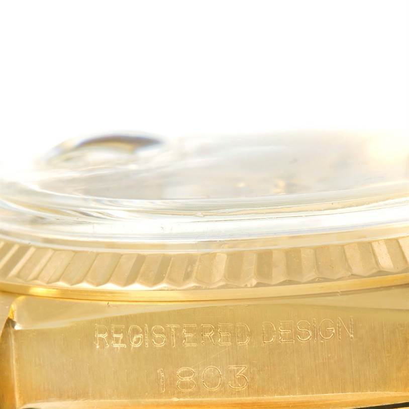 The image shows a close-up of the Rolex President 1803 Men
s Yellow Gold Silver Dial 1803 Men
s Yellow Gold Silver Dial model
s side, focusing on the gold case and "REGISTERED DESIGN 1803" engraving.