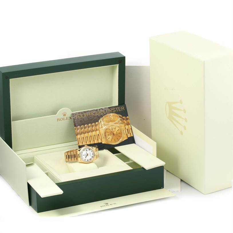 The image shows a Rolex President 118208 Men
s Yellow Gold White Dial 118208 Men
s Yellow Gold White Dial model watch placed in an open box, along with its card and packaging.
