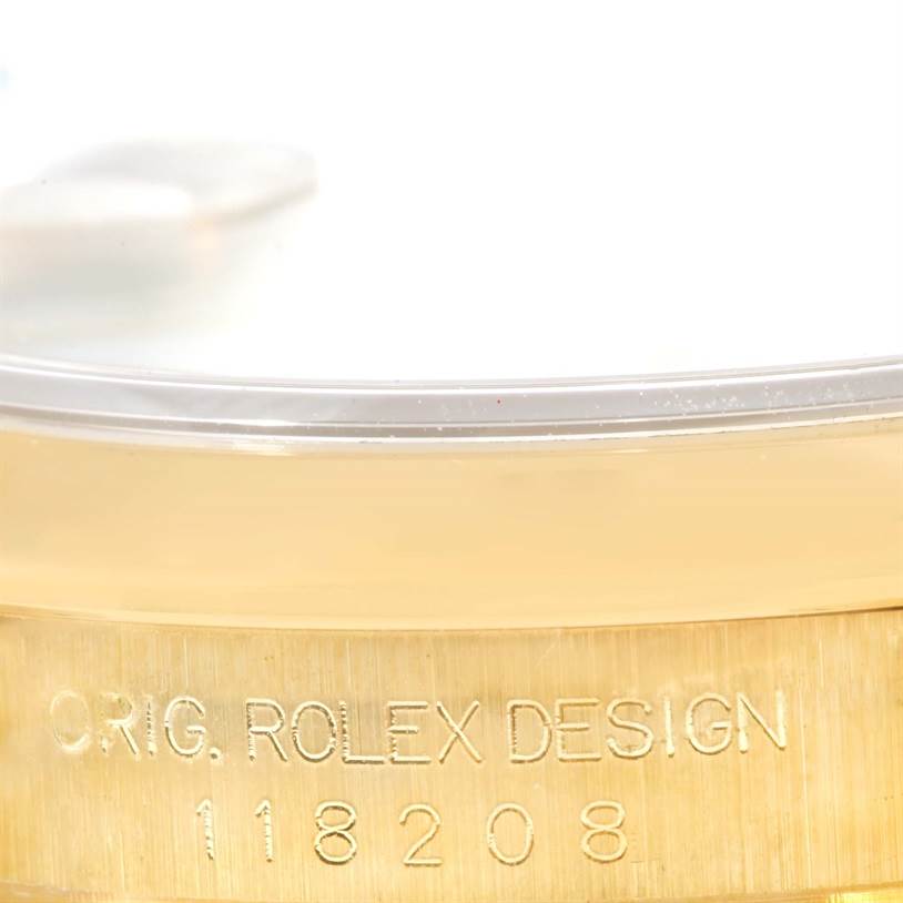 This image shows a close-up of the side of a Rolex President 118208 Men
s Yellow Gold White Dial 118208 Men
s Yellow Gold White Dial model watch, displaying the engraved design serial number.